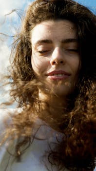 Portrait of a young woman with eyes closed and smiling, enjoying the sunlight with a gentle breeze.